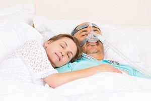 Woman sleeping next to man with CPAP