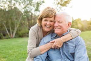 An older couple smiling outside.