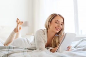 woman on bed writing in journal 