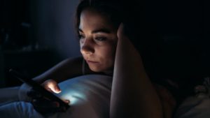 person on their phone in bed at night