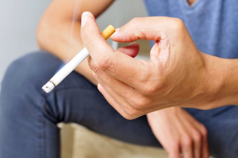 male hand holding lit cigarette