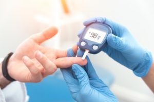 medical professional testing a patient’s blood sugar 