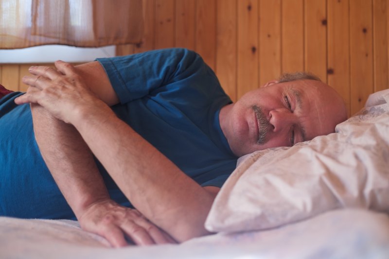 Senior man sleeping on side with sleep apnea in Weatherford