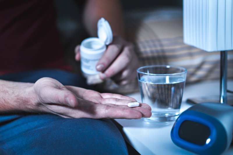 Man in bed holding a sleeping pill