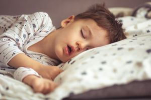 Little boy sleeping in bed while snoring