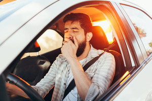 Bearded man sitting in car while yawning