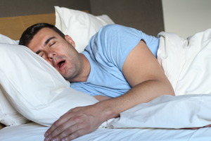 Man with sleep apnea lying in bed and snoring
