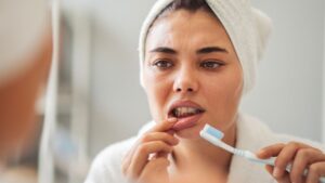 Concerned woman looking at her gums in bathroom mirror